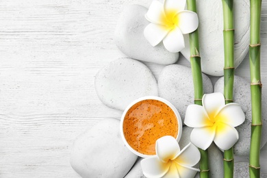 Photo of Flat lay composition with bamboo branches and spa stones on wooden background. Space for text