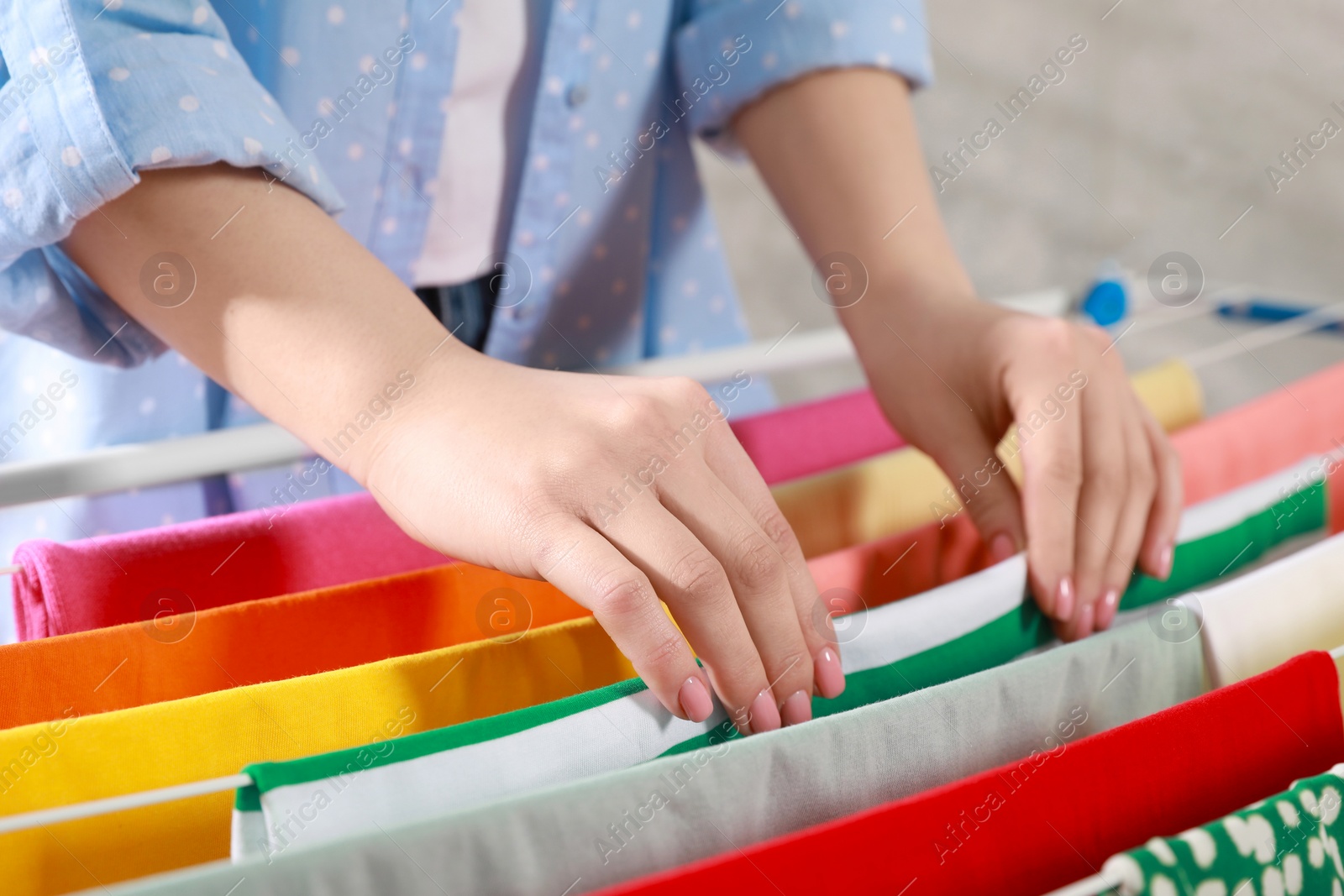 Photo of Woman hanging different apparel on clothes airer, closeup