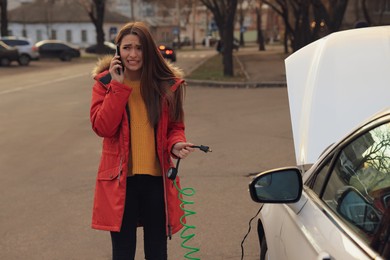 Young woman having difficulties while inflating car tire on street