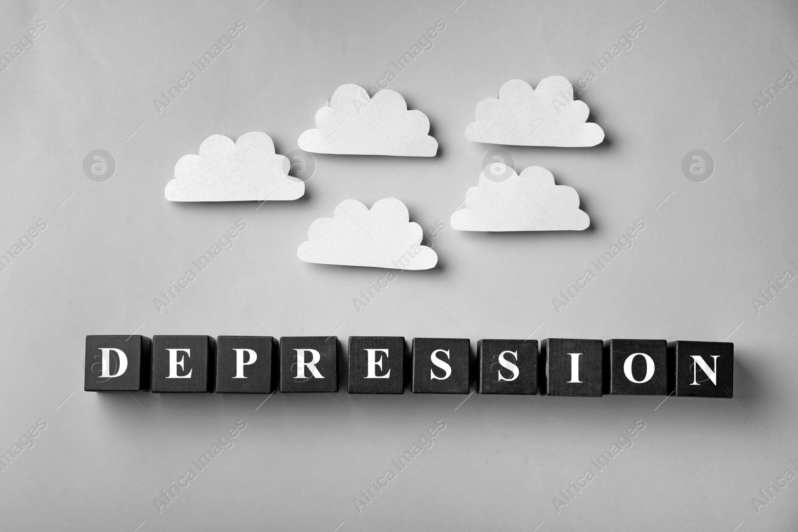 Photo of Word Depression made of black wooden cubes and decorative clouds on light background, top view