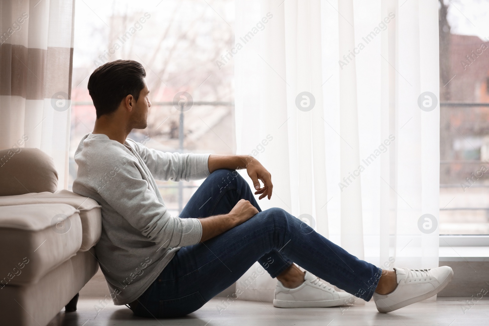 Photo of Man resting on floor near window at home