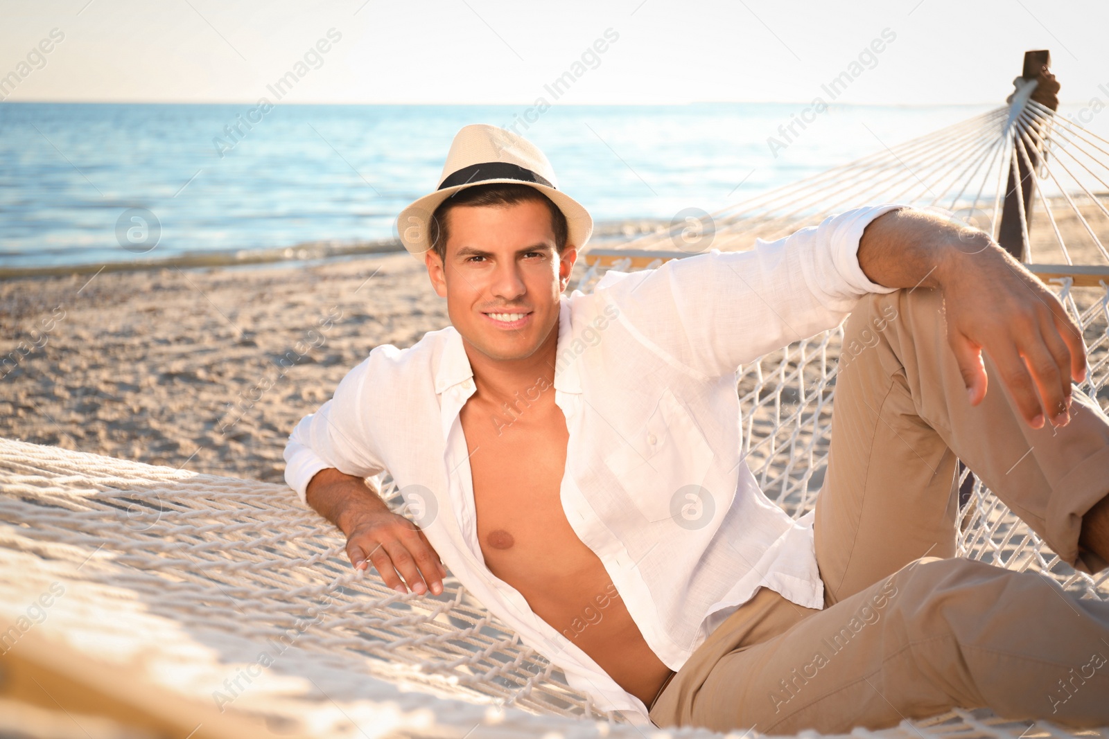 Photo of Man relaxing in hammock on beach. Summer vacation