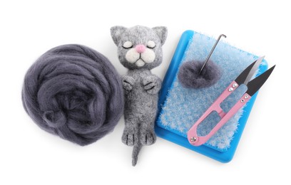 Photo of Needle felted cat, wool and tools isolated on white, top view