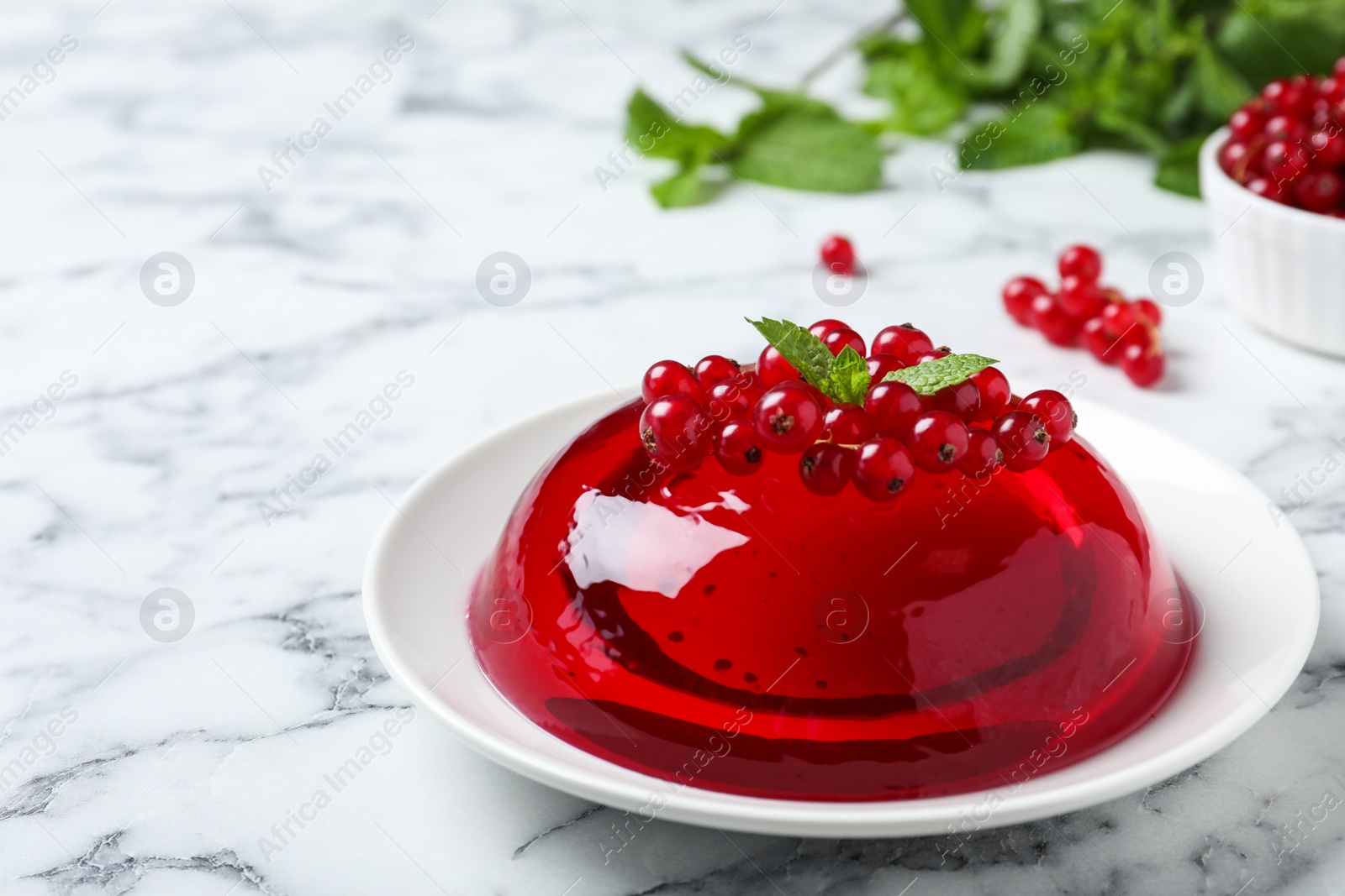 Photo of Delicious fresh red jelly with berries and mint on marble table