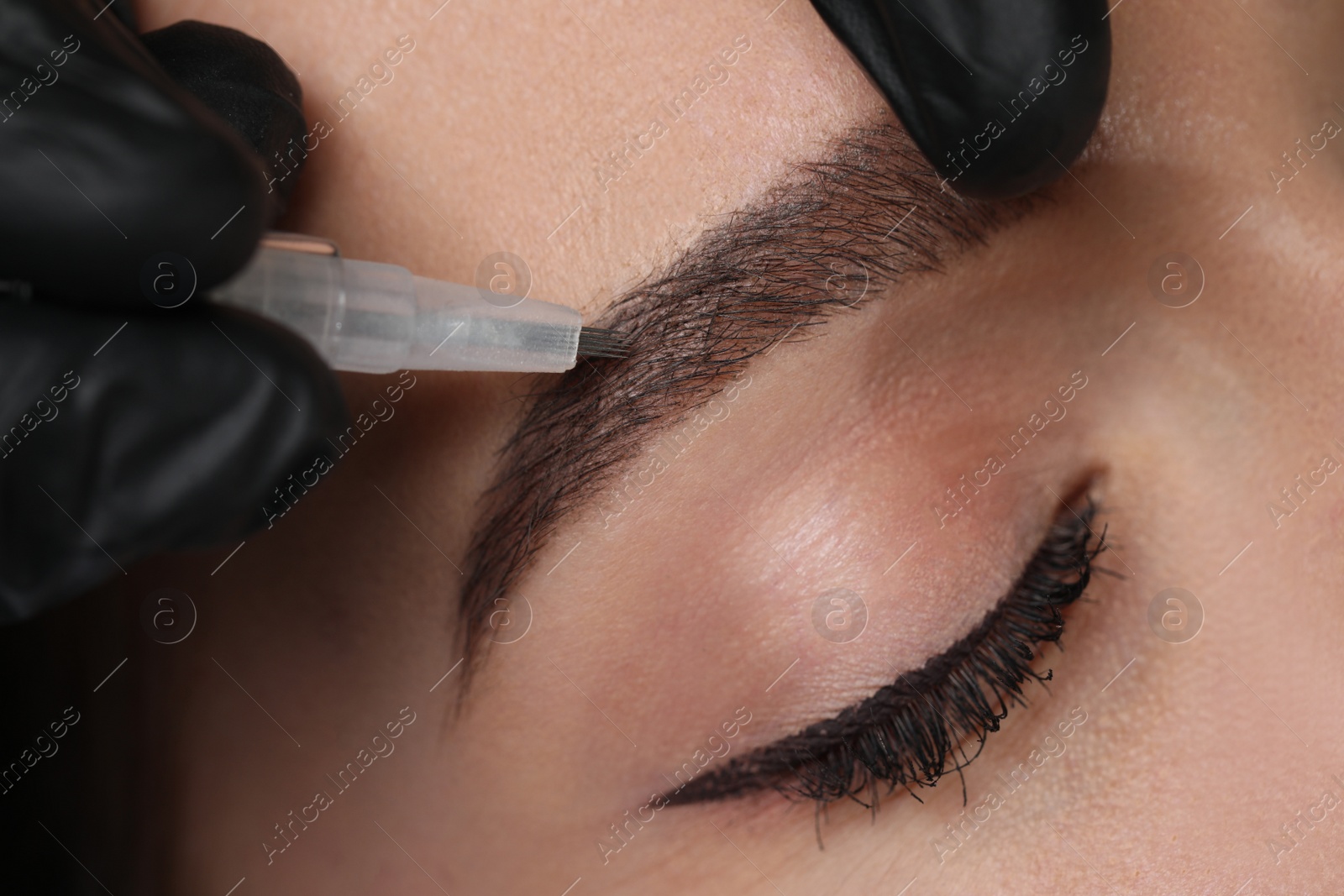 Photo of Young woman during procedure of permanent eyebrow makeup, closeup