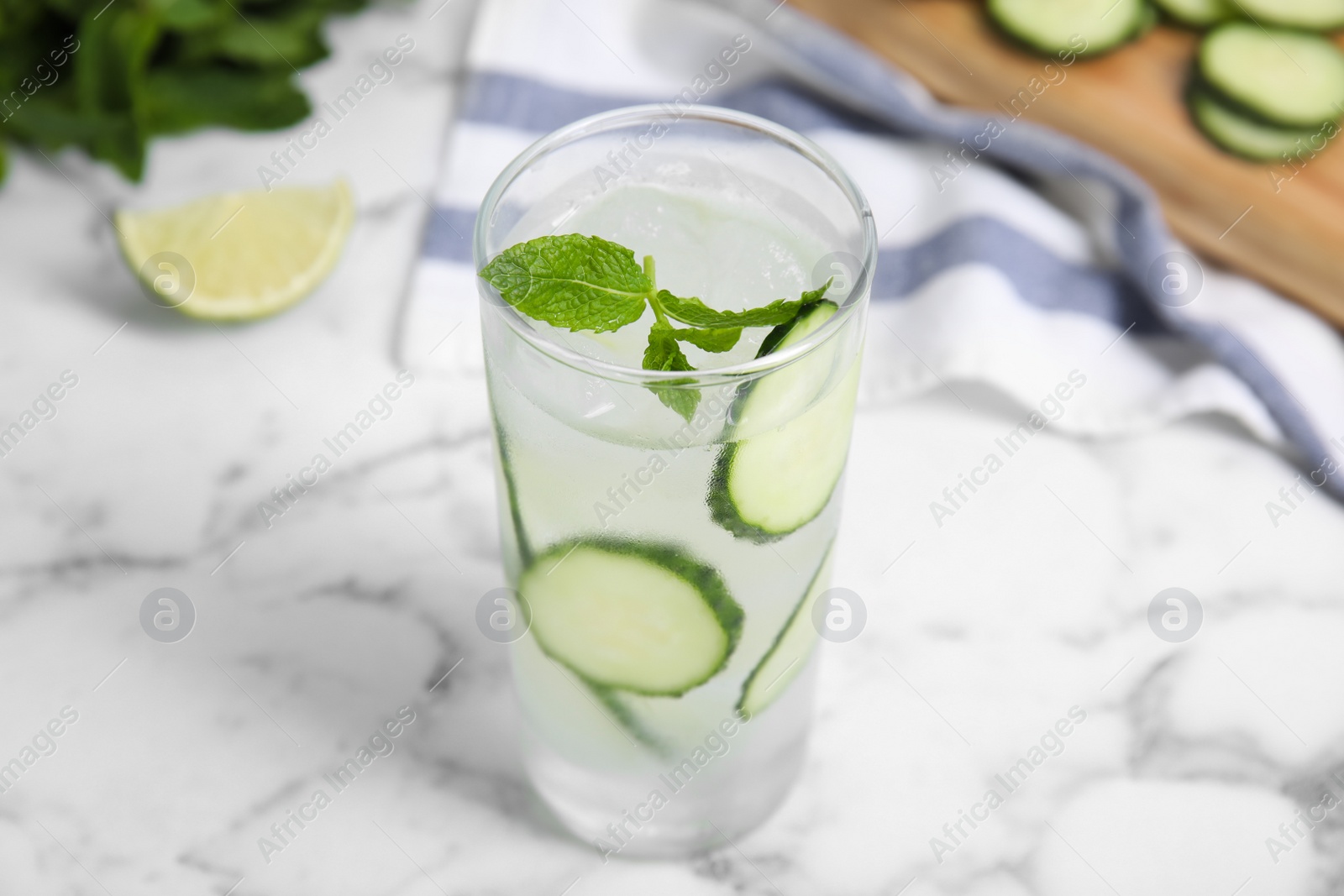 Photo of Glass of refreshing cucumber water with mint on white marble table