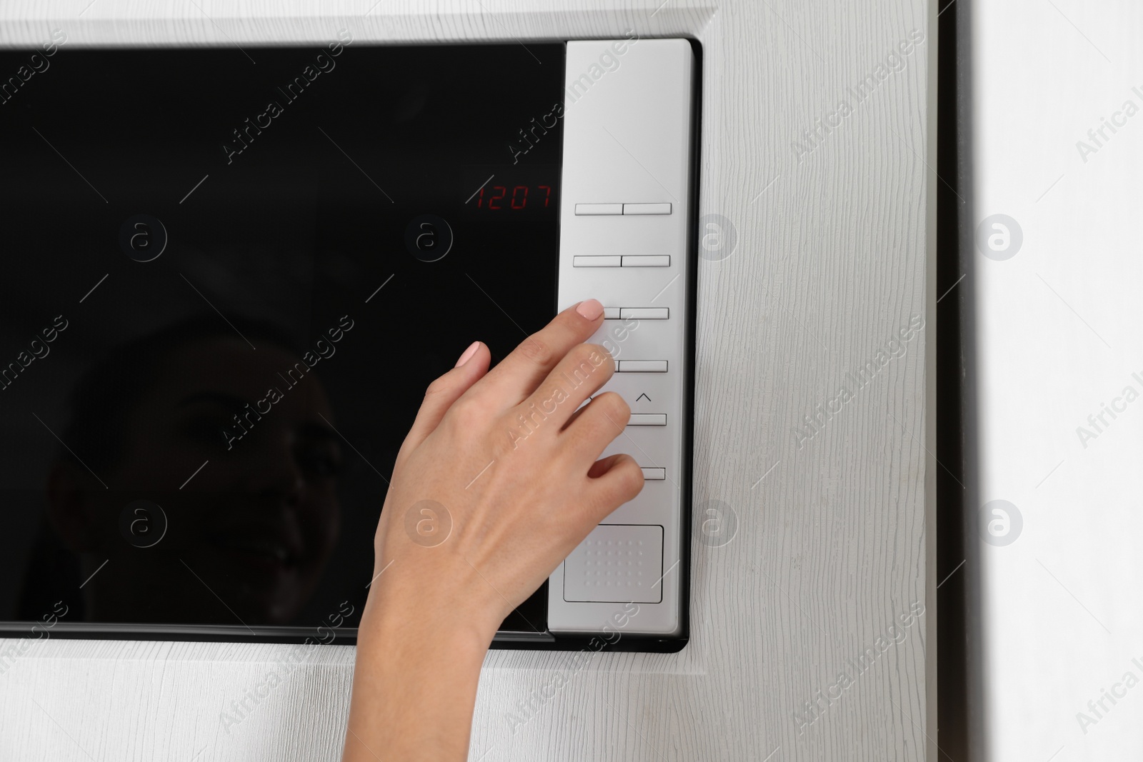 Photo of Young woman using microwave oven, closeup view