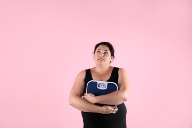 Photo of Overweight woman in sportswear with scales on color background