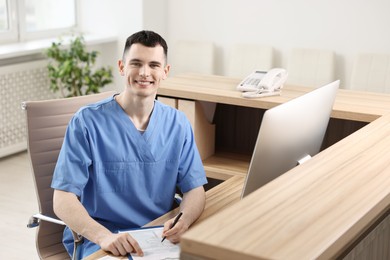 Photo of Smiling medical assistant with clipboard at hospital reception