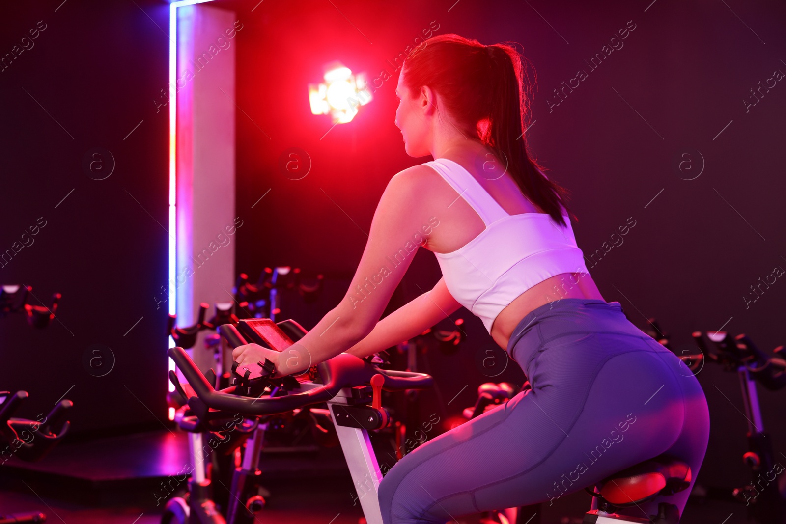 Photo of Young woman training on exercise bike in fitness club