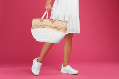 Photo of Young woman with stylish straw bag on pink background, closeup