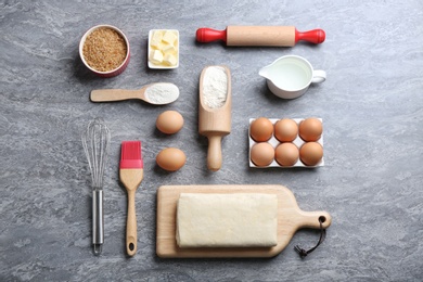 Flat lay composition with puff pastry dough and ingredients on grey table