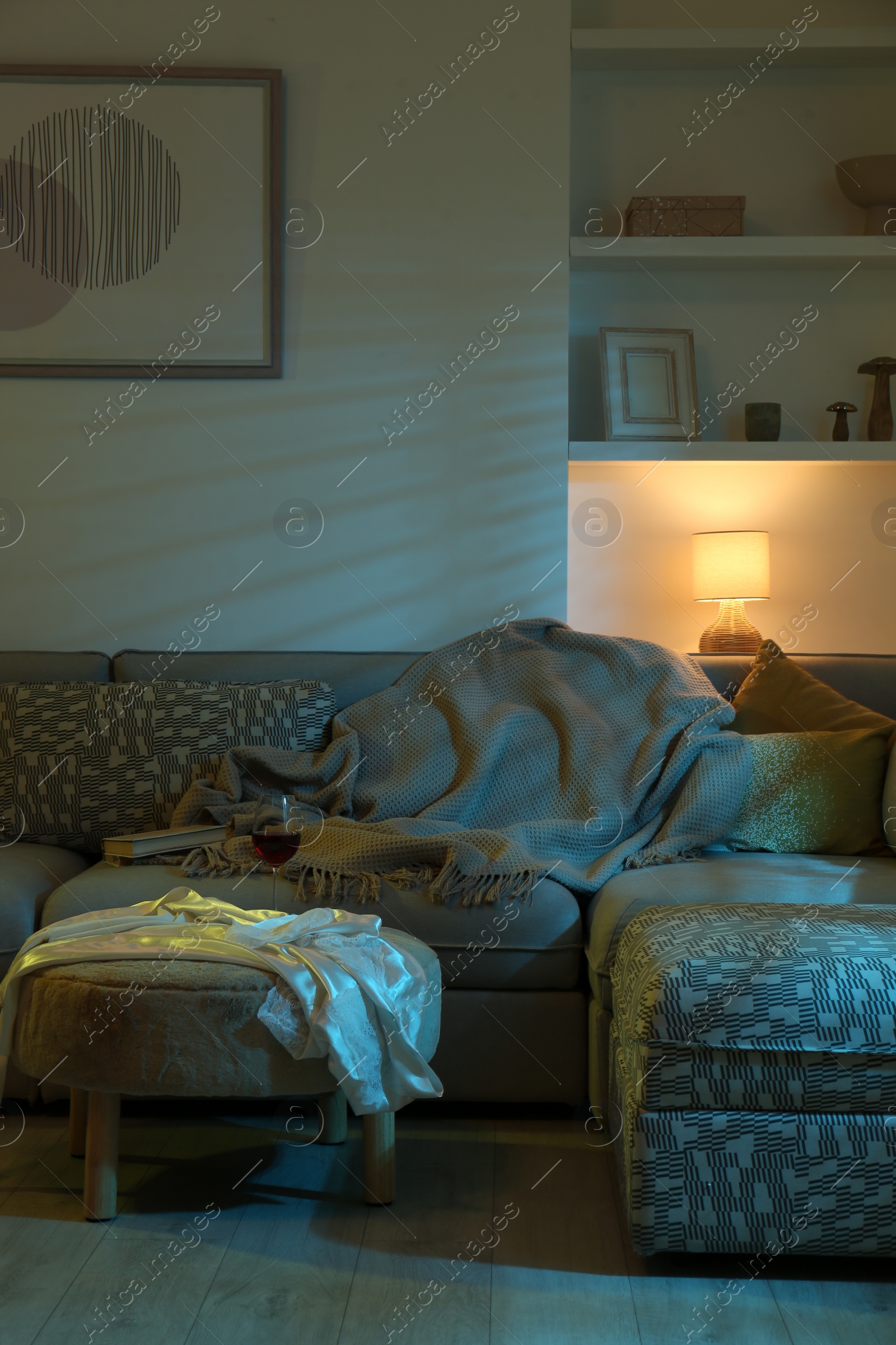 Photo of Stylish room interior with couch and lamp at night