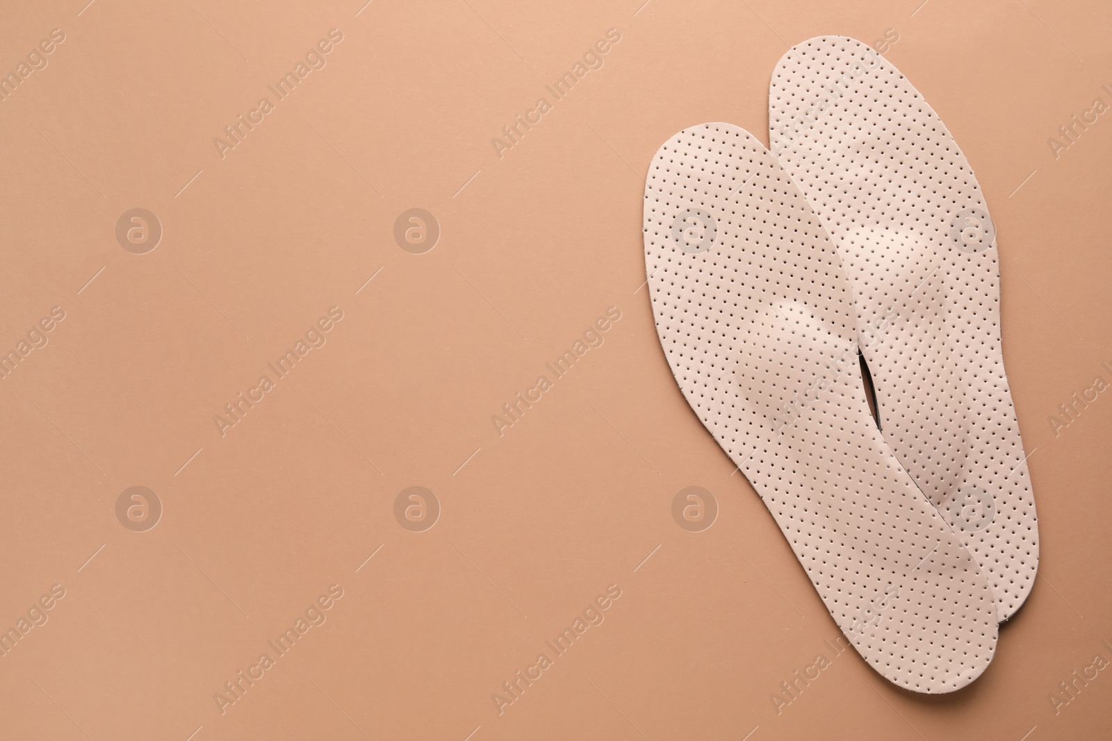 Photo of Orthopedic insoles on pale pink background, flat lay. Space for text