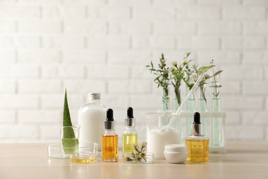 Photo of Organic cosmetic products, natural ingredients and laboratory glassware on wooden table