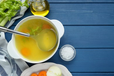 Photo of Delicious chicken bouillon and ingredients on blue wooden table, flat lay. Space for text