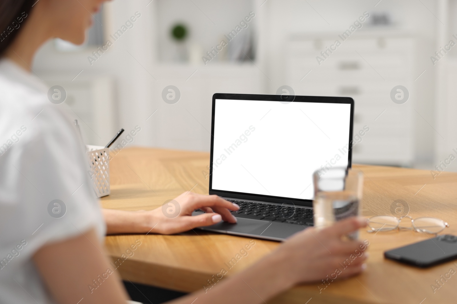 Photo of Young woman watching webinar at table in room, closeup