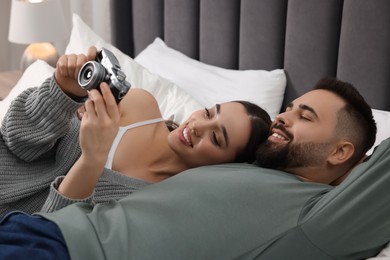 Happy young couple with camera on bed