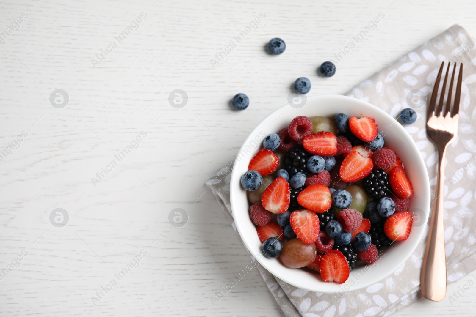 Photo of Fresh tasty fruit salad on white wooden table, flat lay. Space for text