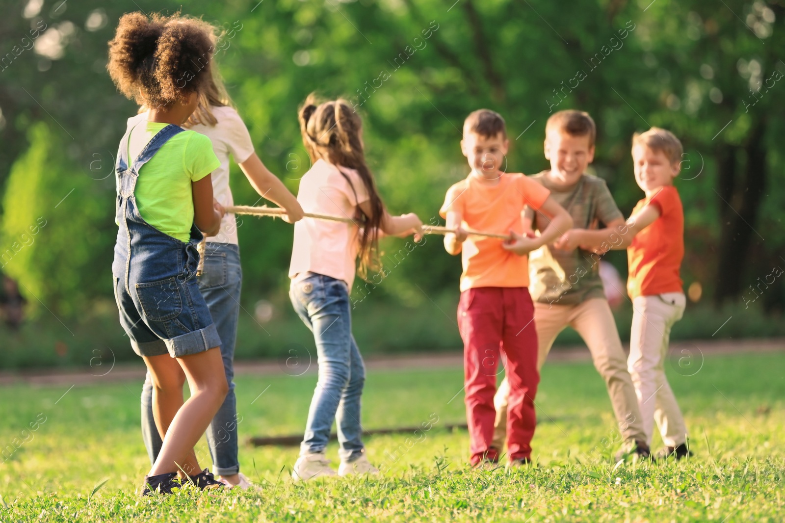 Photo of Cute little children playing with rope outdoors on sunny day