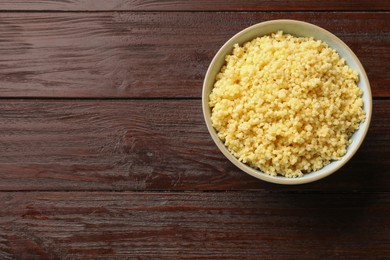 Photo of Tasty millet porridge in bowl on wooden table, top view. Space for text