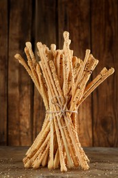 Photo of Bunch of delicious grissini sticks on wooden table