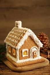 Photo of Beautiful gingerbread house decorated with icing on wooden table