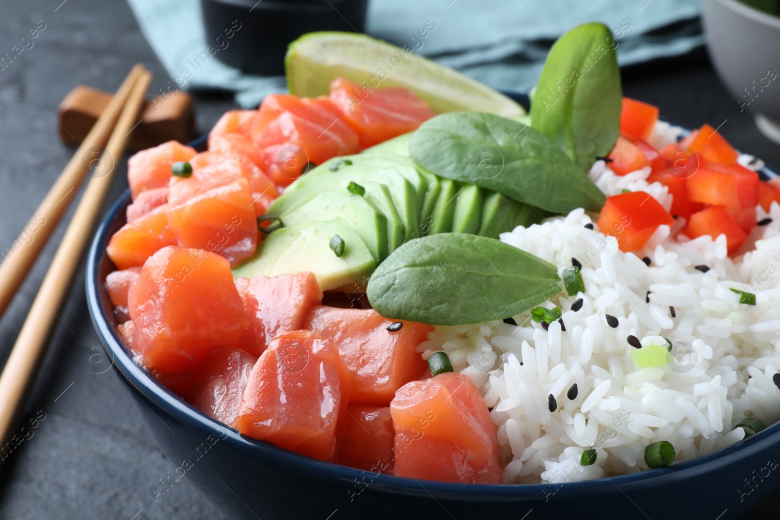 Photo of Delicious poke bowl with salmon, spinach and avocado served on black table, closeup