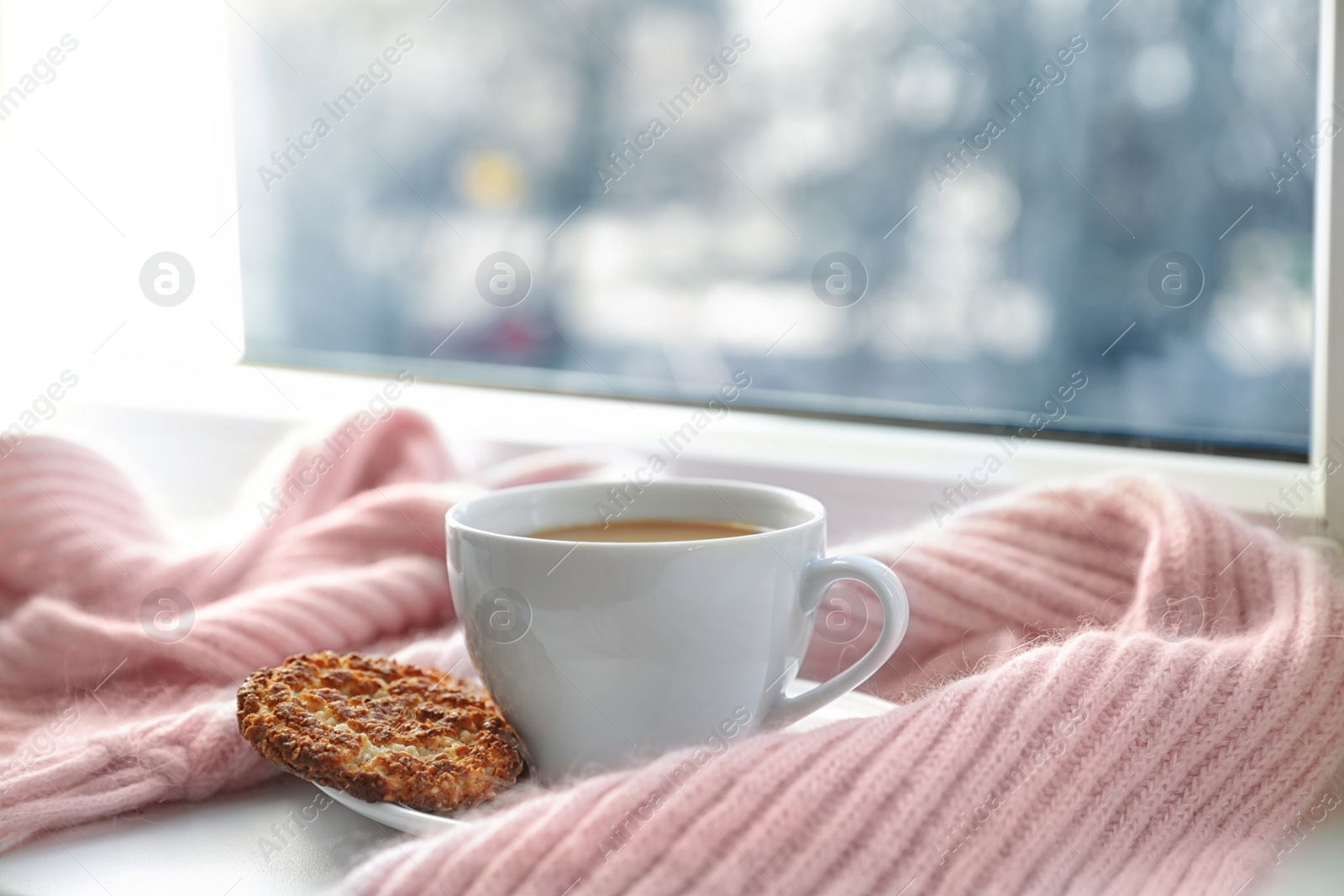 Photo of Cup of winter drink, cookie and knitted scarf on windowsill. Space for text