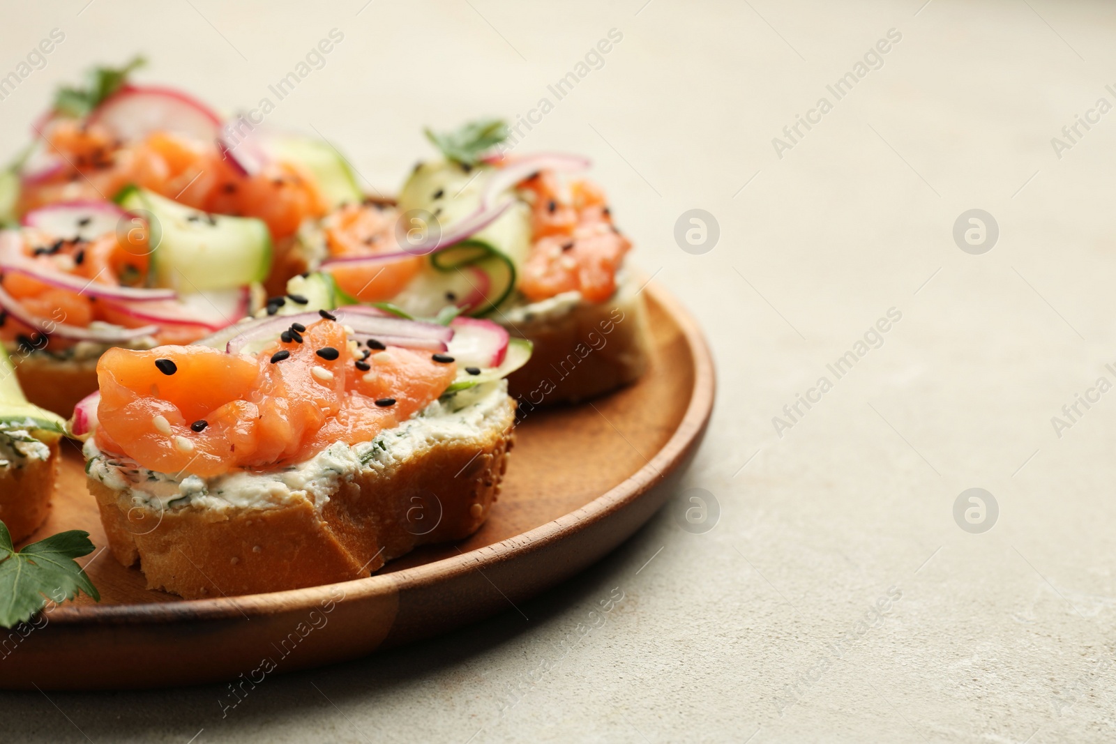 Photo of Tasty canapes with salmon served on light grey table, closeup. Space for text