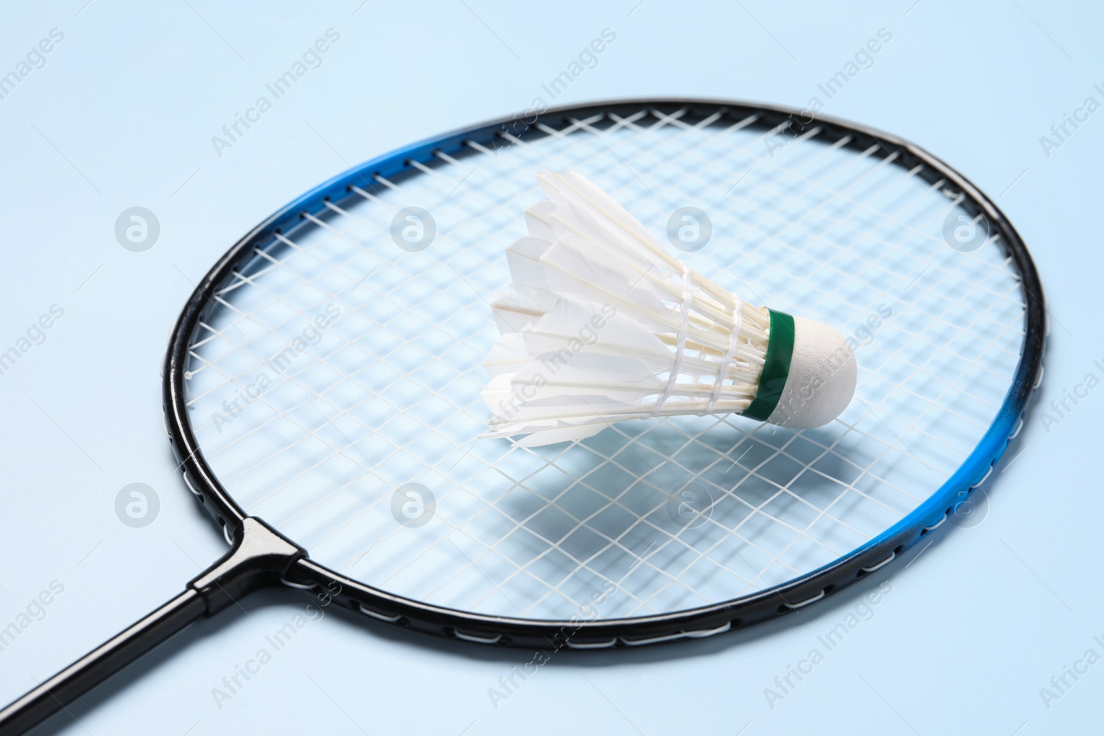 Photo of Feather badminton shuttlecock and racket on light blue background, closeup