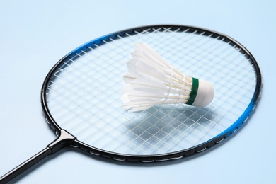 Feather badminton shuttlecock and racket on light blue background, closeup