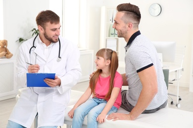 Father and daughter visiting pediatrician. Doctor working with patient in hospital