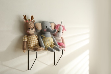 Photo of Shelf with cute toys on light wall. Baby room interior element