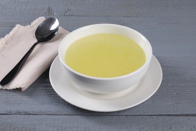 Photo of Tasty broth in bowl on grey wooden table