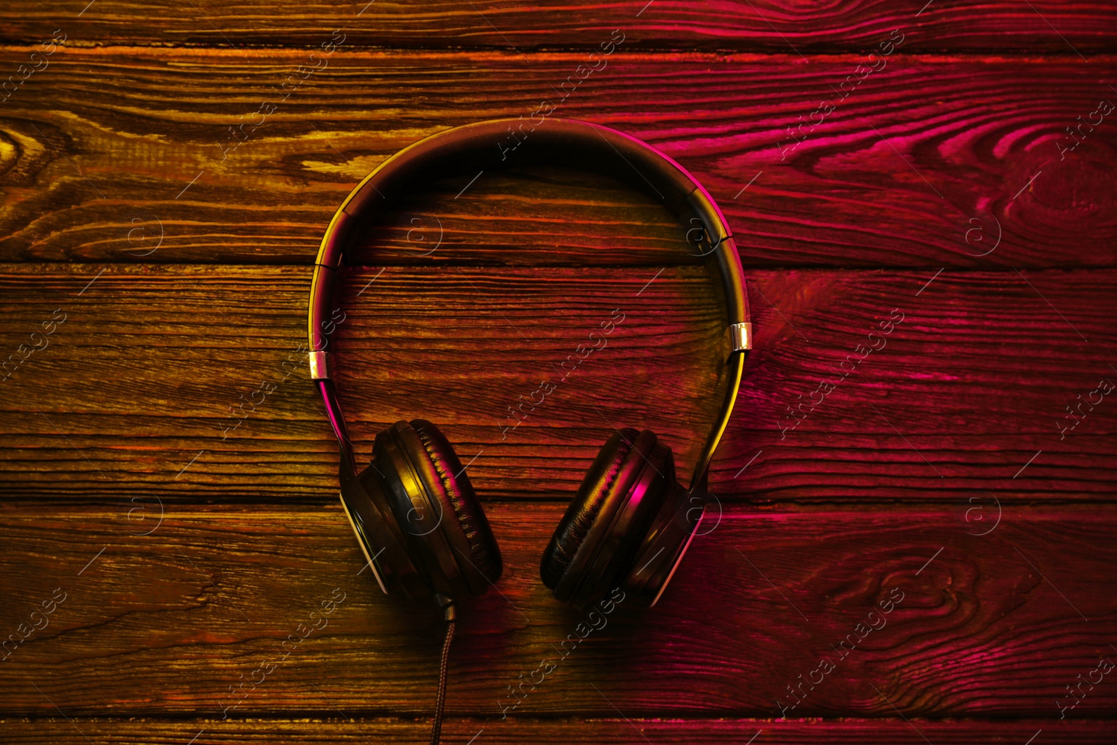 Photo of Stylish modern headphones with earmuffs on wooden background, top view