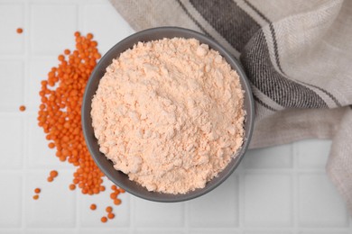 Bowl of lentil flour and seeds on white tiled table, flat lay