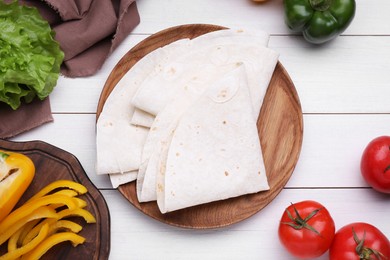 Photo of Delicious folded Armenian lavash and fresh vegetables on white wooden table, flat lay