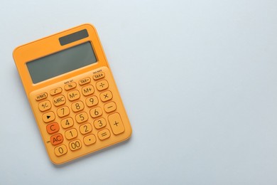 Photo of Orange calculator on light background, top view. Space for text