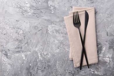 Photo of Elegant cutlery and kitchen towel on grey textured table, top view. Space for text