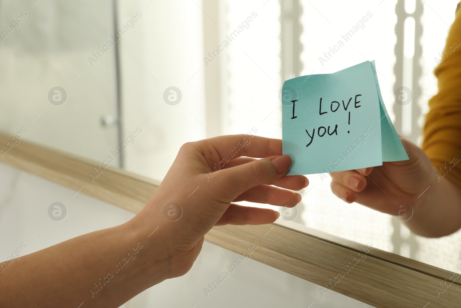 Photo of Woman putting sticky note with text I love you! on mirror, closeup