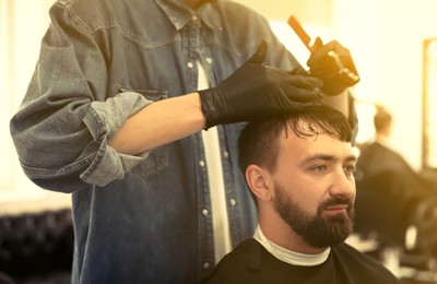 Image of Professional barber working with client in hairdressing salon