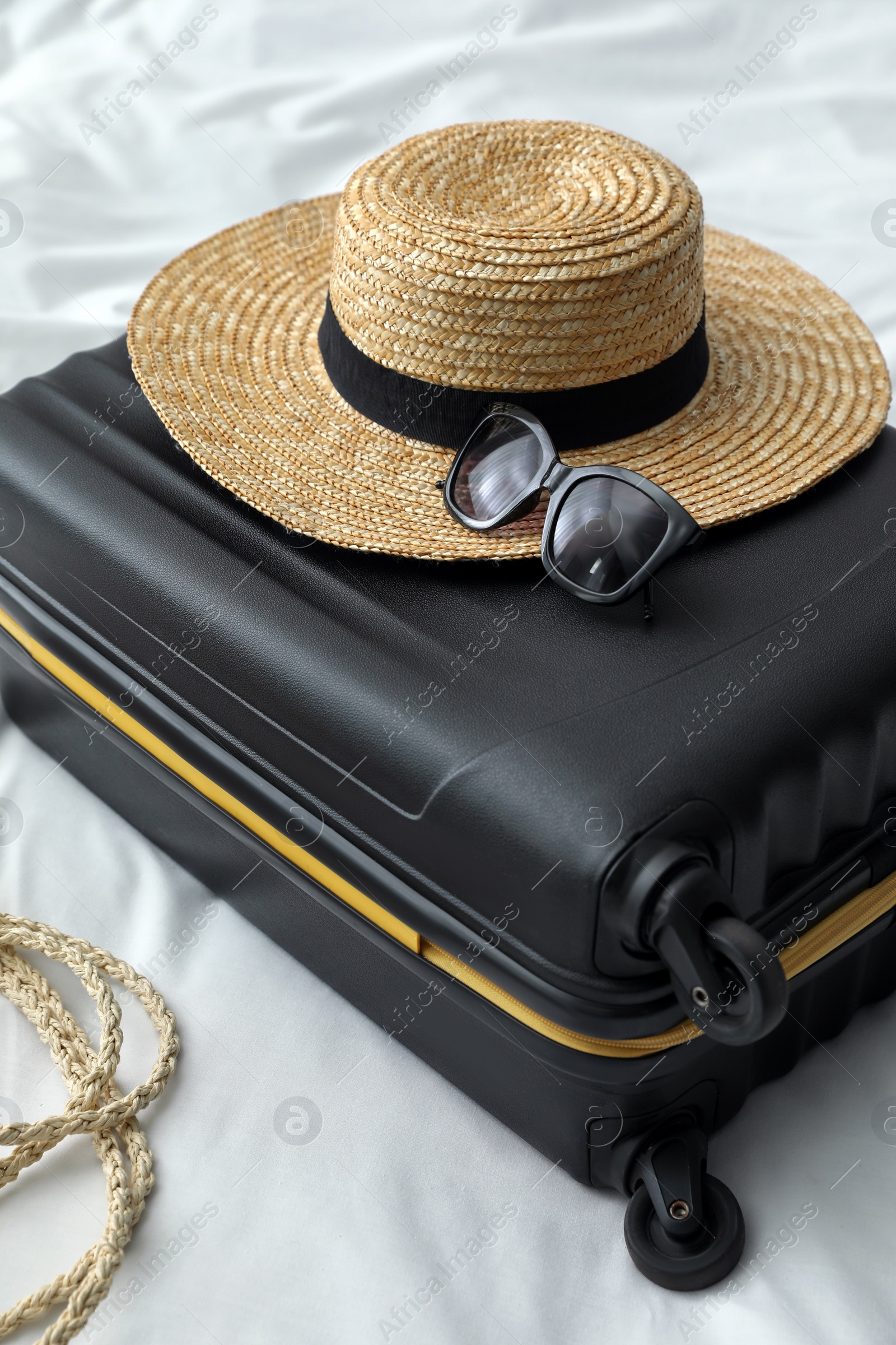 Photo of Suitcase packed for trip and summer accessories on bed