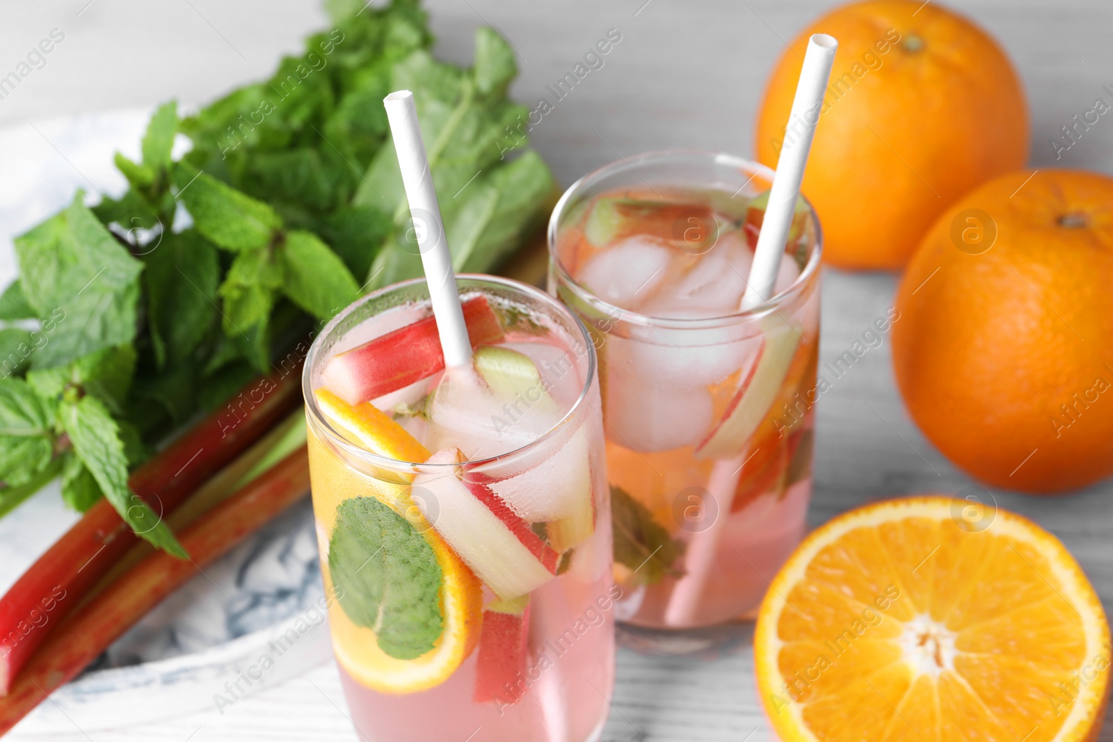 Photo of Tasty rhubarb cocktail with orange on white wooden table