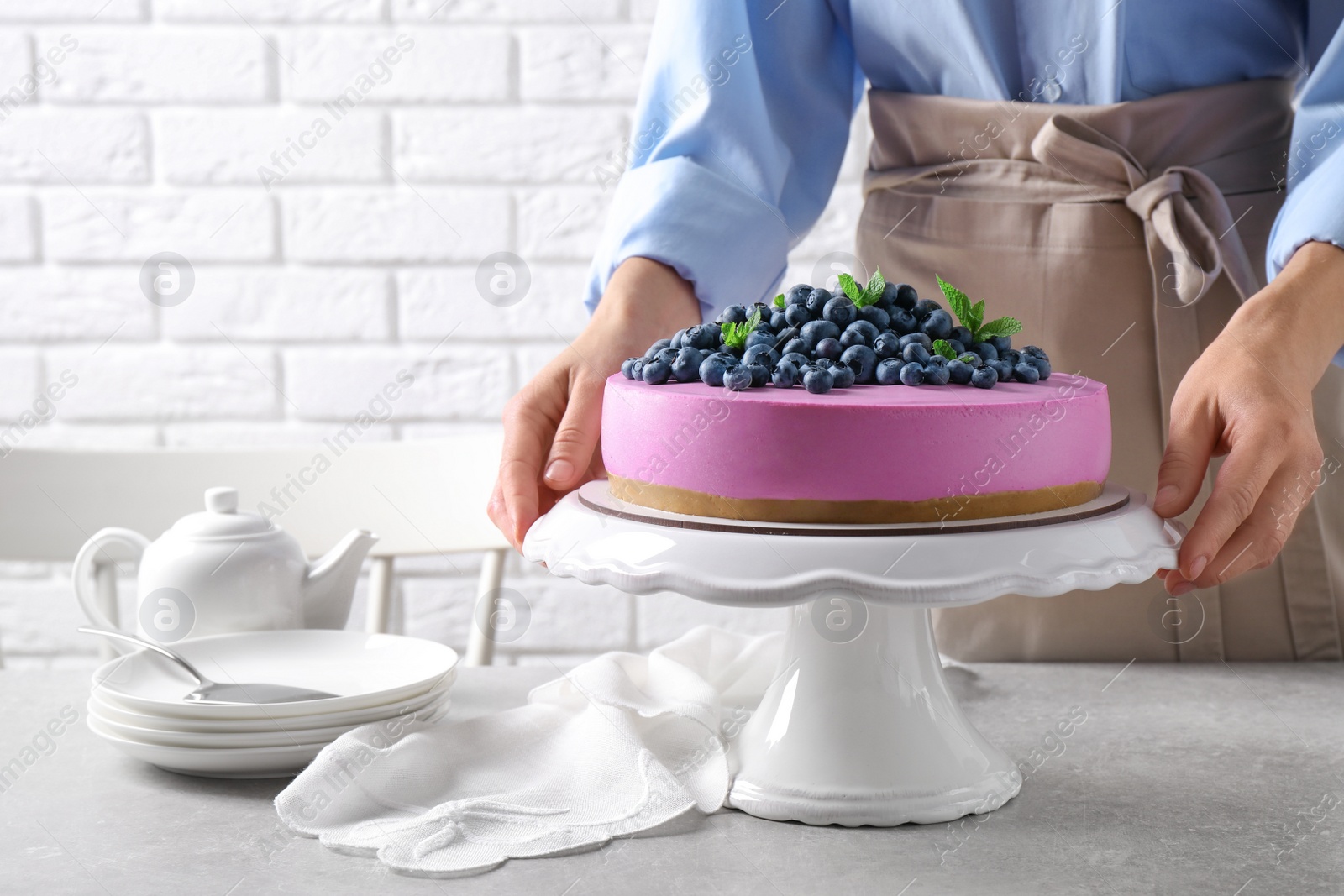 Photo of Young woman with tasty blueberry cake at grey table, closeup