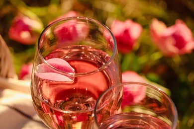 Photo of Glassdelicious rose wine with petals outside, closeup