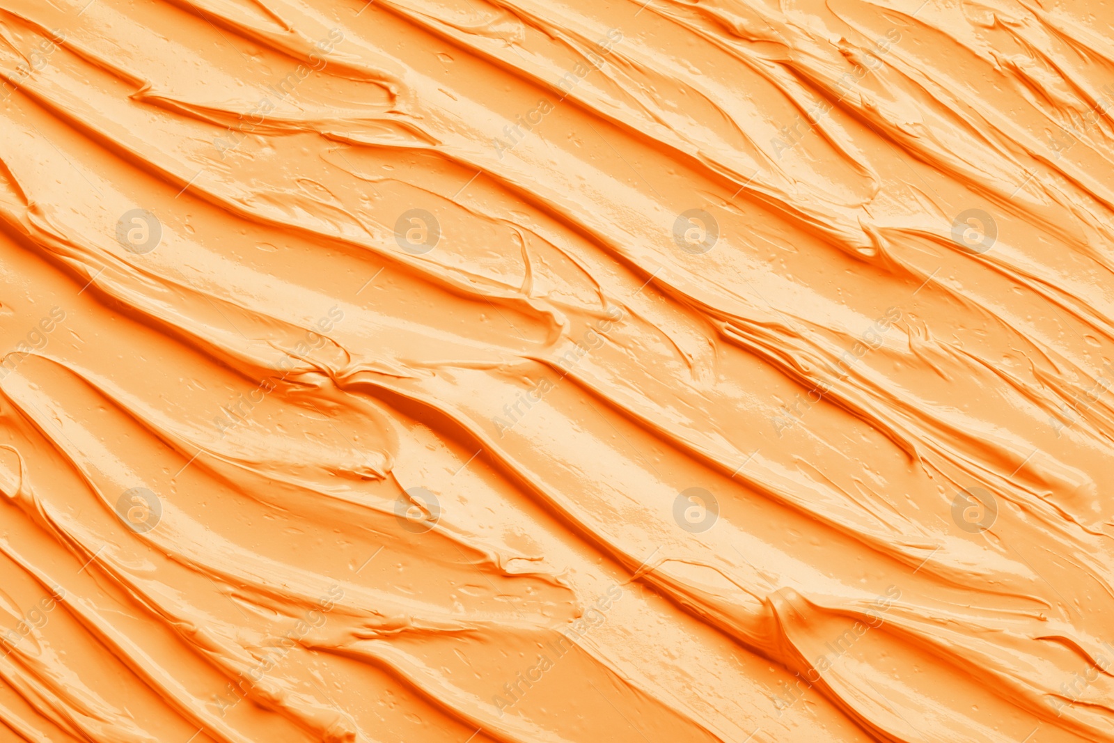Image of Strokes of pale orange oil paint as background, closeup