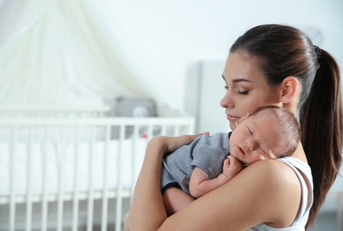 Photo of Young woman with her newborn baby at home. Space for text