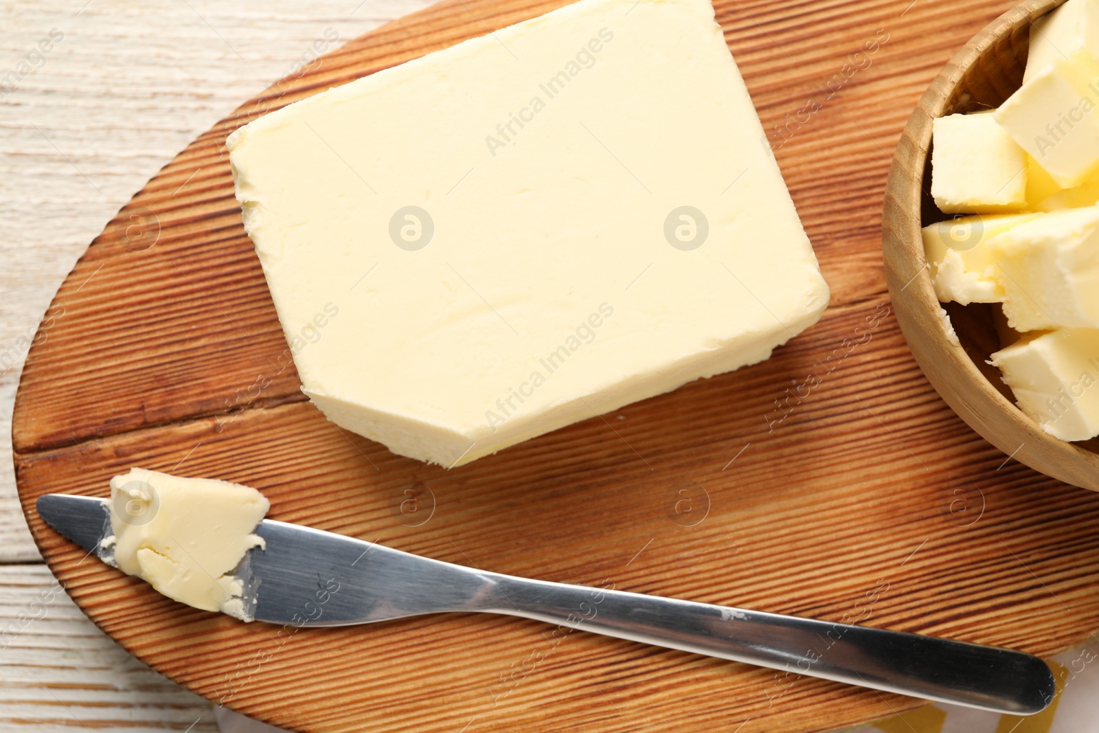 Photo of Tasty butter and knife on light wooden table, top view