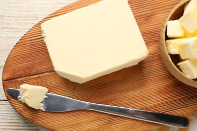 Photo of Tasty butter and knife on light wooden table, top view